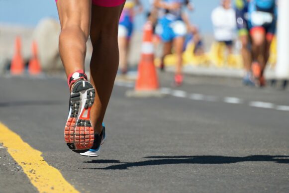 A marathon runner wearing tennis shoes is shown from behind