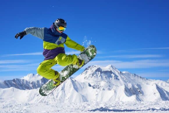 A man in yellow snowsuit is snowboarding against a bright, blue sky