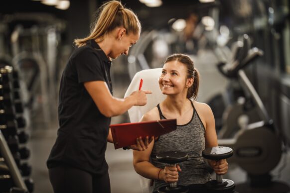 A physical therapist and personal trainer chat in the gym.