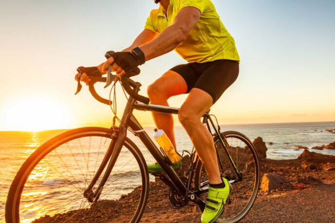 A man riding a bike at sunset along a coast