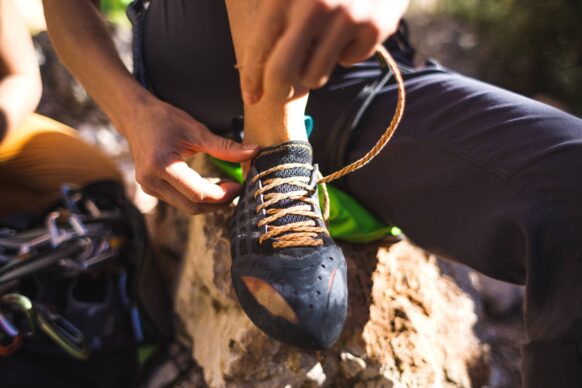 A rock climber prepares for a climb by lacing up his shoes