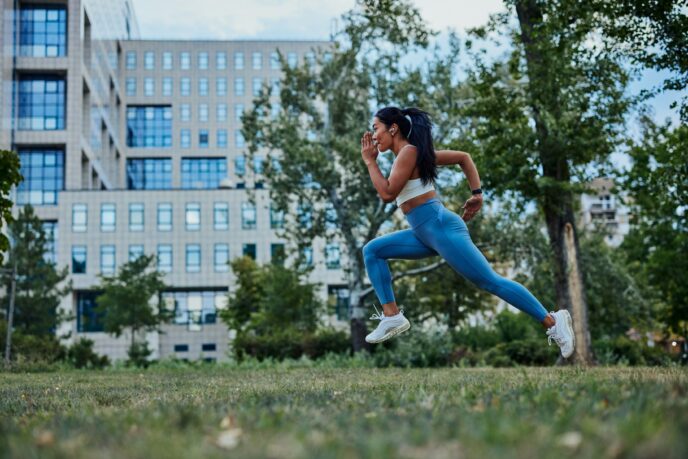 A young asian woman in blue exercise pants is doing sprinting exercises in the park