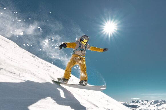 A snowboarder balances on his board as he glides down a slope