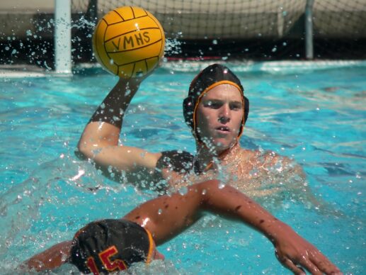 Man doing an eggbeater kick about to throw a ball during a water polo match